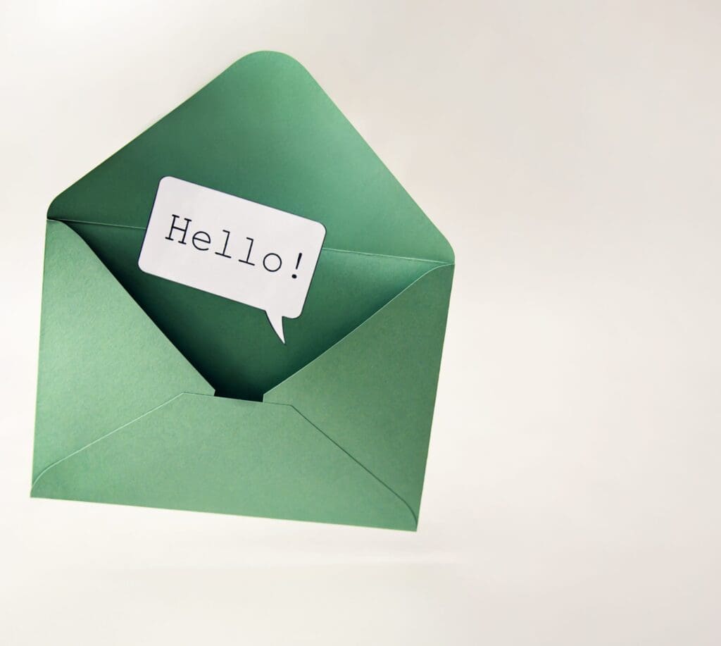 A green envelope is open with a white card inside that reads "Hello!" in a speech bubble style on a plain background.