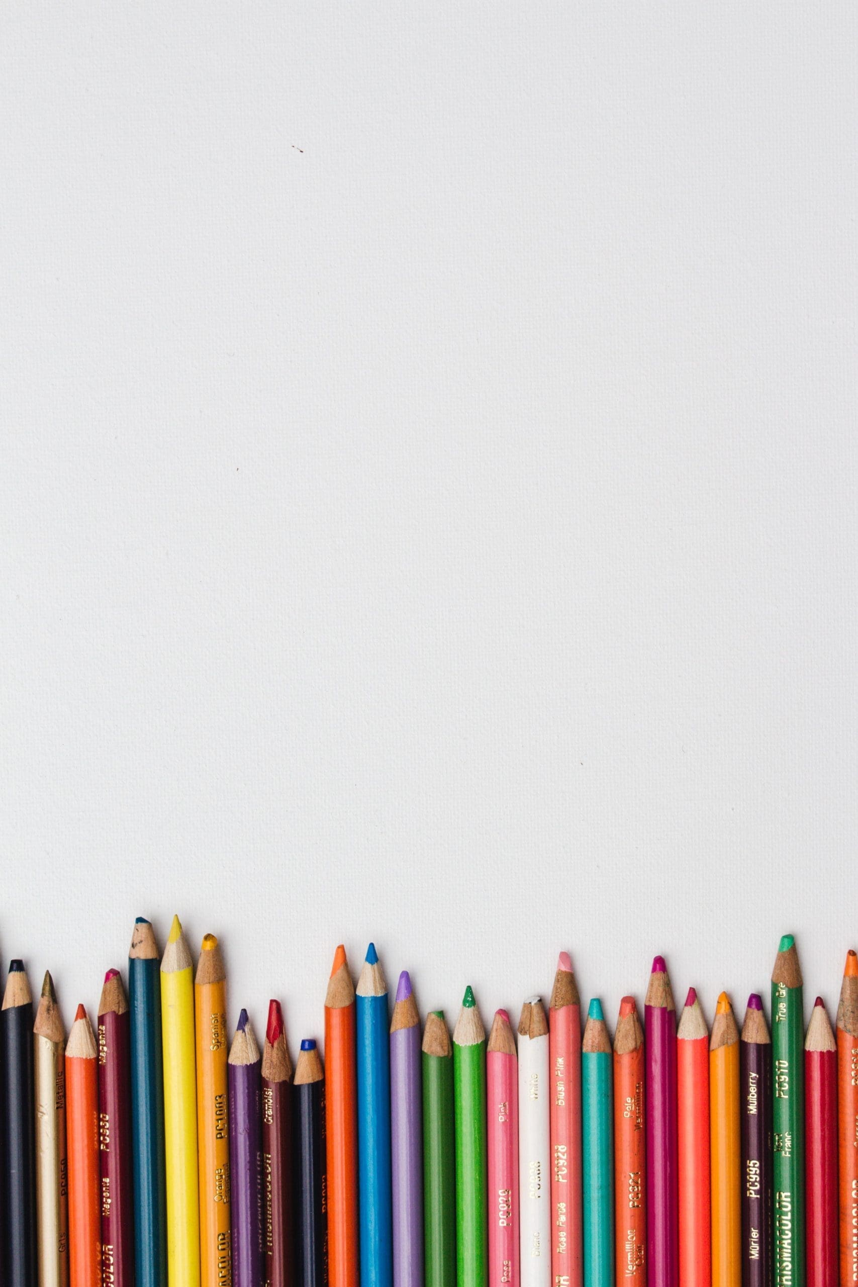 A row of sharpened colored pencils in various hues is arranged vertically at the bottom against a plain white background.